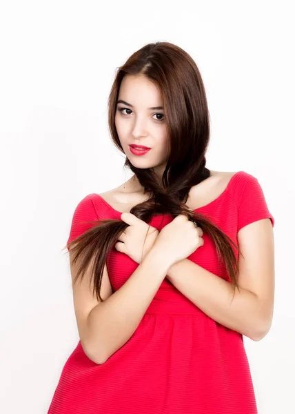 Bela jovem vestida com um vestido vermelho, segura tranças. estúdio tiro — Fotografia de Stock