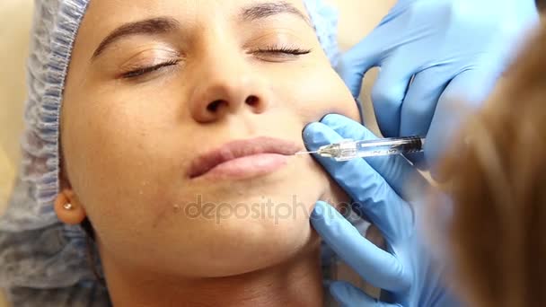 Jonge vrouw op de lip vergroting in een kliniek. Verdoving injectie siliconen implantaat lippen verdikking. Botox injectie — Stockvideo