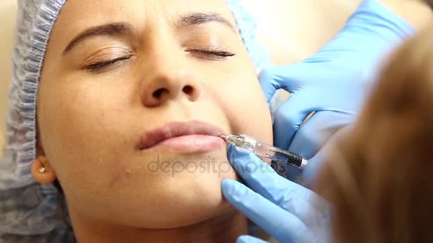 Jonge vrouw op de lip vergroting in een kliniek. Verdoving injectie siliconen implantaat lippen verdikking. Botox injectie — Stockvideo