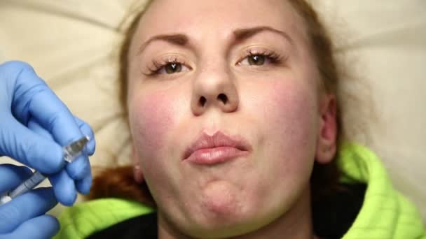 Mujer joven en labio Aumento en una clínica. Inyección anestésica Engrosamiento de labios con implante de silicona. inyección de botox — Vídeo de stock