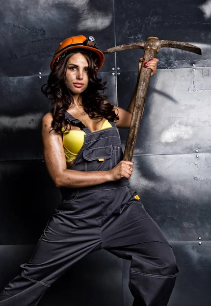 Sexy žena horník dělník s krumpáčem v kombinéze nad jeho nahé tělo — Stock fotografie