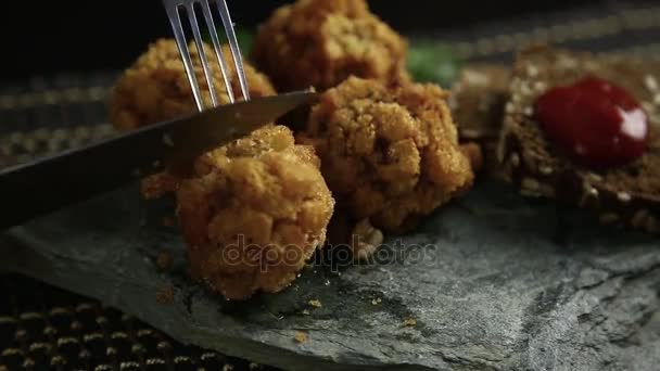 Homemade meat cutlets in batter with parsley, ketchup and bread on stone, woman cutting food to knife — Stock Video