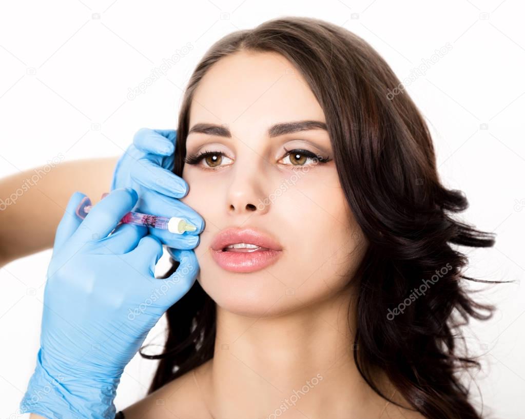young woman gets beauty injection in eye and lips area from beautician. cosmetology concept