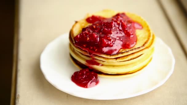 Zelfgemaakte zoete pannenkoeken met fruit jam en zure room op een witte plaat. Ontbijt met stapel bijgevuld bosbessen jam en walnoten. — Stockvideo