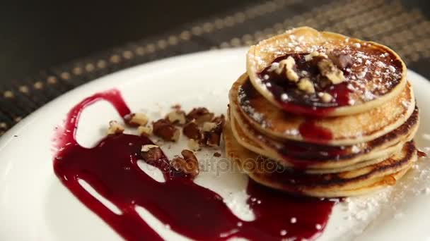 Panqueques dulces caseros con mermelada de frutas, crema agria en un plato blanco. Desayuno con mermelada de arándanos rematada y nueces . — Vídeo de stock