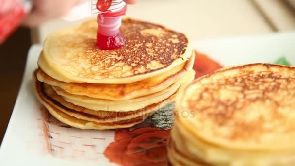 Zelfgemaakte zoete pannenkoeken met fruit jam en zure room op een witte plaat. Ontbijt met stapel bijgevuld bosbessen jam en walnoten. — Stockvideo