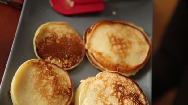 Cocinar preparar el desayuno o el postre, freír panqueques en un gribble. Panqueques dulces caseros con mermelada de frutas, crema agria en un plato blanco . — Vídeo de stock