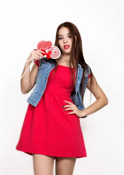 Красива молода жінка, одягнена в червону сукню, тримає льодяник, студійний знімок — стокове фото