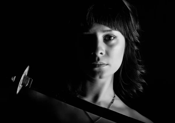 Mulher close-up com espada no fundo escuro. preto e branco — Fotografia de Stock