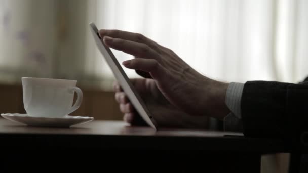 Hombre usando tableta PC y beber café. Las manos de cerca sobre el fondo de la ventana — Vídeo de stock