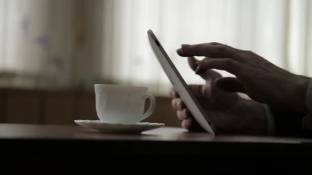 Ο άνθρωπος χρησιμοποιώντας tablet Pc και πίνοντας καφέ. Κινηματογράφηση σε πρώτο πλάνο τα χέρια σε ένα φόντο παράθυρο — Αρχείο Βίντεο