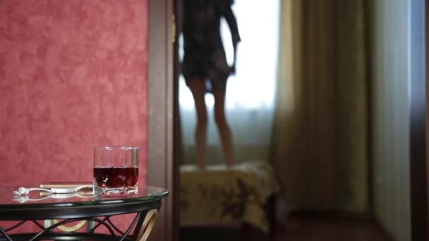Dronken Arabische meisje grappige springen op een bed. Close-up glas cognac — Stockvideo