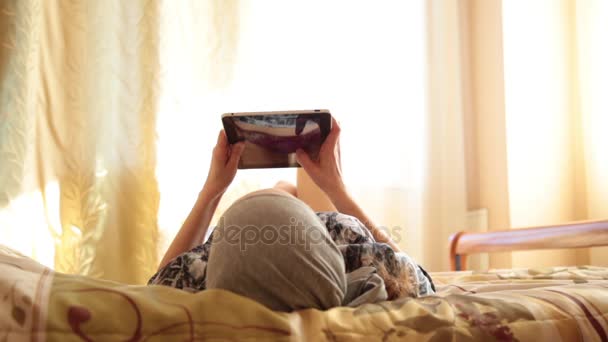 自宅の寝室のベッドでタブレット pc コンピューターと若いアラブの少女。女性が画面に反映されます。技術と人々 の概念 — ストック動画