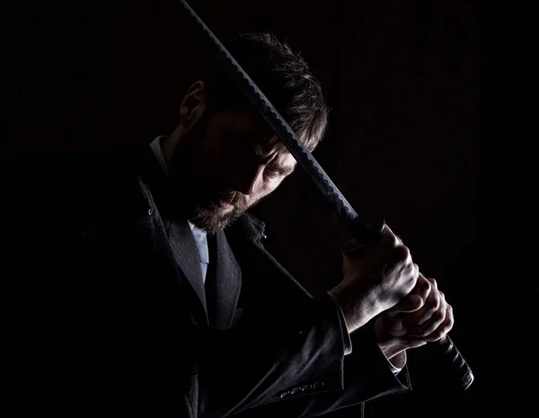 Stern zły biznesmen w płaszcz z wełny z mieczem w ciemnym tle — Zdjęcie stockowe
