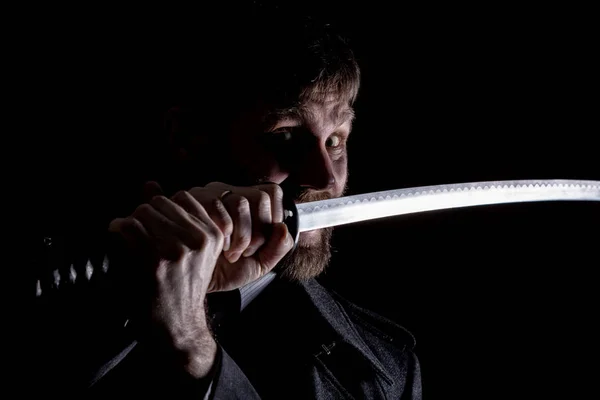 Strenger, wütender Geschäftsmann im Wollmantel mit Schwert im dunklen Hintergrund — Stockfoto