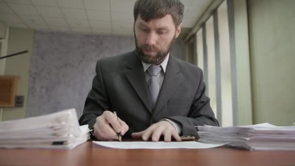 Busy office worker sadly shakes his head, signing and stamping incoming documents — Stock Video