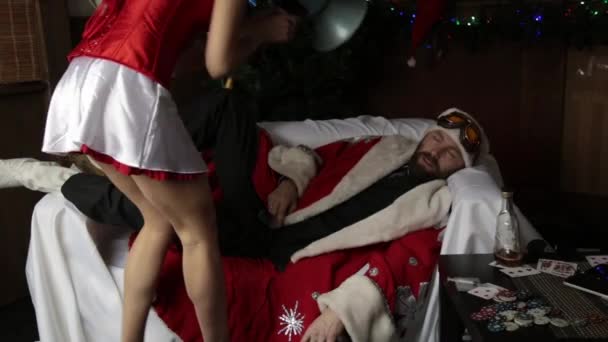 Pijany Mikołaj leżąc na kanapie, kobiece pielęgniarka sexy kobieta w karnawał kostium gospodarstwa bullhorn, próbuje go obudzić — Wideo stockowe