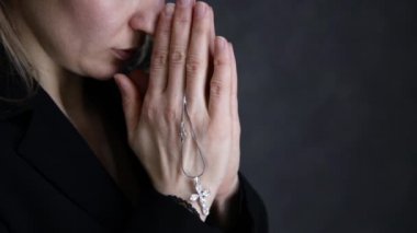 genç kadın dua ediyor. zincir bir haç ile tutarak yakın çekim eller