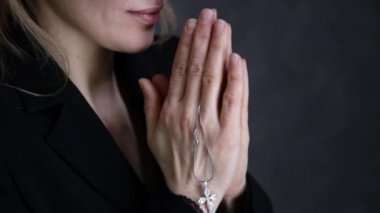 genç kadın dua ediyor. zincir bir haç ile tutarak yakın çekim eller