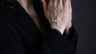 genç kadın dua ediyor. zincir bir haç ile tutarak yakın çekim eller