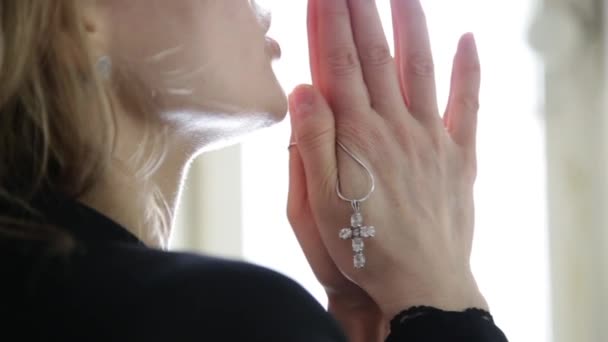 Молода жінка молиться. крупним планом жіночі руки тримають ланцюг з хрестом — стокове відео