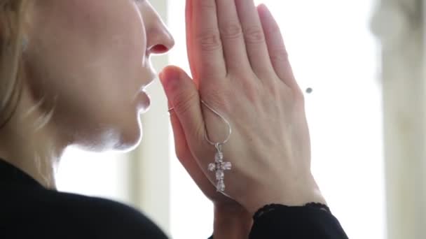 Giovane donna sta pregando. mani femminili close-up che tengono la catena con una croce — Video Stock