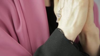 genç kadın başörtüsü dua ediyor. zincir bir haç ile tutarak yakın çekim eller