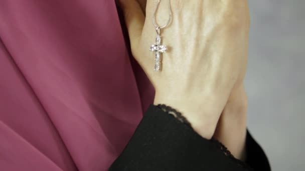 Young woman in headscarf is praying. close-up female hands holding chain with a cross — Stock Video