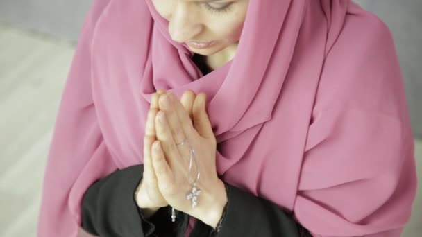 Junge Frau mit Kopftuch betet. Nahaufnahme weibliche Hände, die Kette mit Kreuz halten — Stockvideo