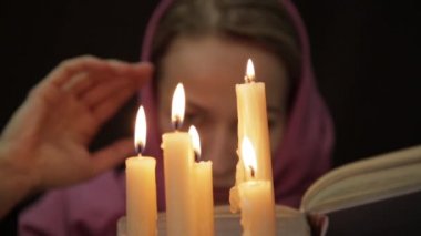 sihirli ritüel yapıyor bir başörtüsü kadında. birkaç mum yakın ve eski kitap. Halloween veya din kavramı