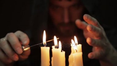 sihirli ayin yapan erkek. birkaç mum yakın ve eski kitap. Büyücü büyü kalın antik kitap mum ışığında çevirir.