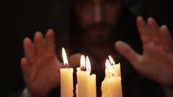 Hombre haciendo el ritual mágico. primer plano varias velas y libro viejo. nigromante lanza hechizos de grueso libro antiguo a la luz de las velas — Vídeo de stock