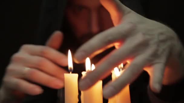 Uomo che fa il rituale magico. primo piano diverse candele e vecchio libro. negromante lancia incantesimi da spessi libri antichi a lume di candela — Video Stock