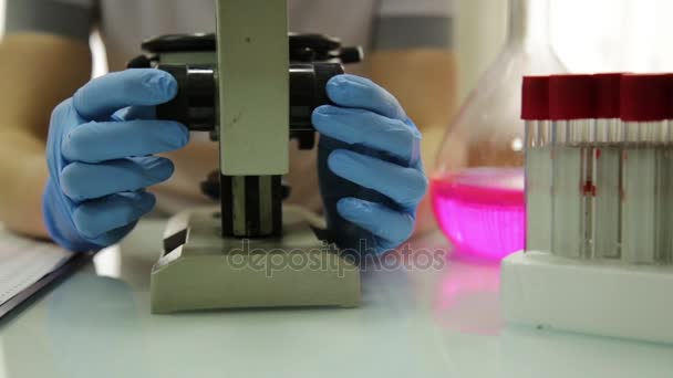 女性医学研究人员使用显微镜和试管在实验室条件下，考察了和记笔记 — 图库视频影像