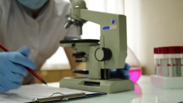 Chercheuses médicales travaillant avec des microscopes et des éprouvettes en laboratoire, étudie et prend des notes — Video