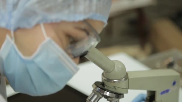 Pesquisadores médicas do sexo feminino que trabalham com microscópios e tubos de ensaio em condições laboratoriais, investiga e toma notas — Vídeo de Stock