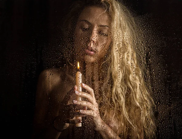 Curly nude blonde woman with candle on dark background — Stock Photo, Image