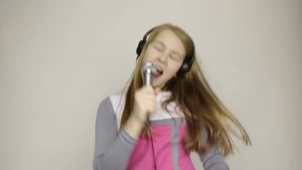 Mladá dívka poslech hudby ve sluchátkách drží mikrofon, funy tanec a zpěv — Stock video