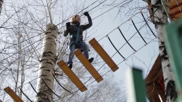 Joven escaladora camina por puente de tronco colgante en curso de cuerdas altas en parque extremo — Vídeo de stock