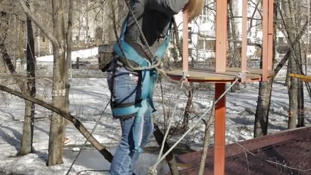 Junge Bergsteigerin wandert über Hängebrücke auf Hochseilgarten im Extrempark — Stockvideo