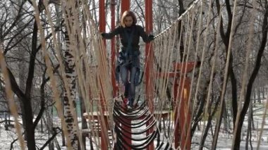 Genç kadın dağcı kolye halat köprü tarafından yüksek halatlar sahası aşırı Park yürür. Kaya tırmanma kavramı