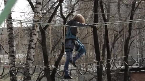 Jeune grimpeuse marche par pendentif pont de corde sur haut parcours de cordes dans le parc extrême. Concept d'escalade — Video