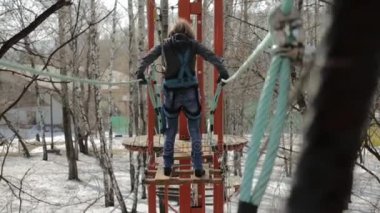 Genç kadın dağcı yüksek halatlar sahası aşırı Park kolye günlük köprü ile yürür. Kaya tırmanma kavramı.