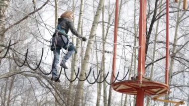 Genç kadın dağcı kolye halat köprü tarafından yüksek halatlar sahası aşırı Park yürür. Kaya tırmanma kavramı