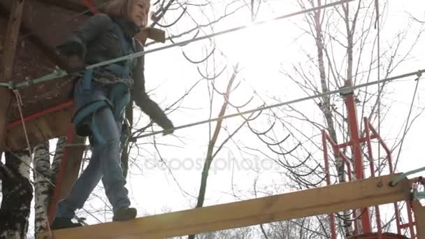 Unga kvinnliga klättrare går förbi hänge log bridge på hög rep kurs i extreme park — Stockvideo