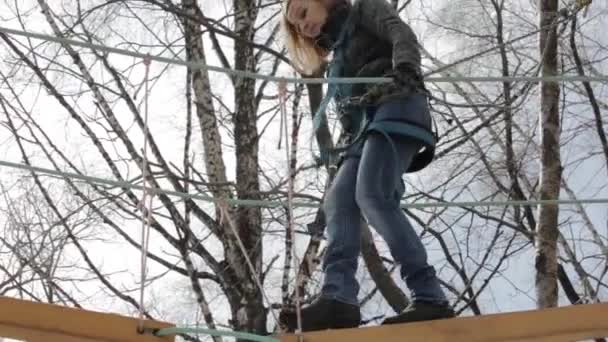 Joven escaladora camina por puente de tronco colgante en curso de cuerdas altas en parque extremo — Vídeos de Stock