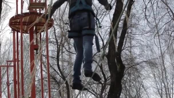 Молода жінка альпіністка прогулюється підвісним мостом на високих канатах в екстремальному парку. концепція скелелазіння — стокове відео