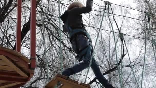 Joven escaladora camina por puente de tronco colgante en curso de cuerdas altas en parque extremo — Vídeos de Stock