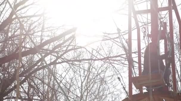 Молодая альпинистка ходит по веревочному мосту на высокой веревке в экстремальном парке. Концепция скалолазания — стоковое видео
