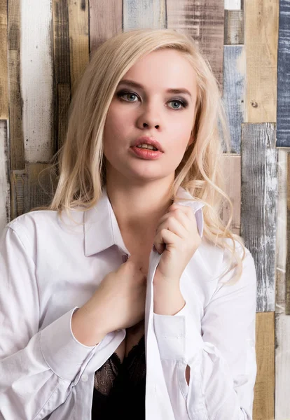 Porträt eines attraktiven blonden Mädchens auf Holz Wandhintergrund. sie hat blaue Augen und trägt ein Herrenhemd — Stockfoto